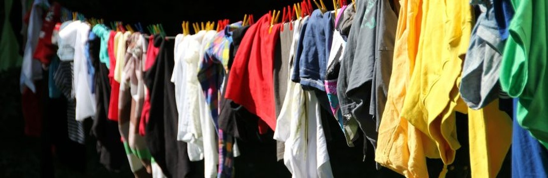 Klädstång fylld med färgglada second hand-kläder i en butik.