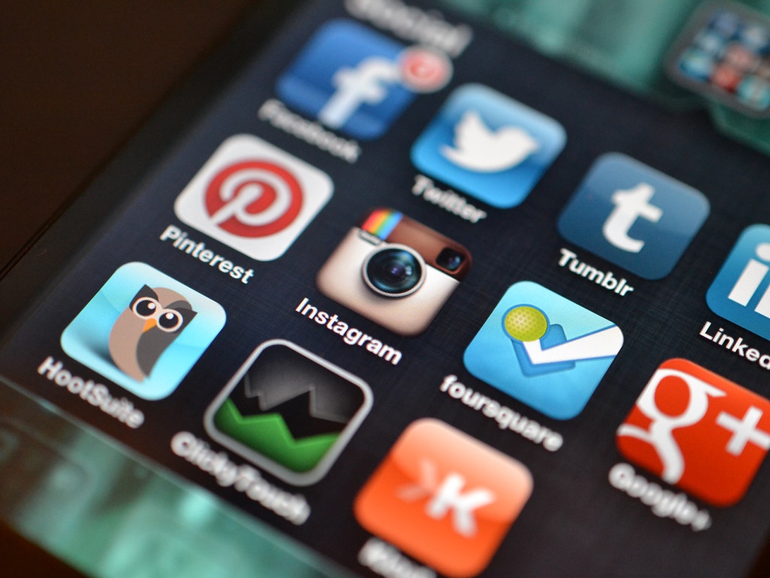 En närbild av en smarttelefonskärm som visar olika ikoner för sociala medieapplikationer inklusive Instagram, Pinterest, Twitter, Facebook och andra – alla plattformar som vanligtvis används för upptäckt, delning och influencer-marknadsföring av modeinnehåll.